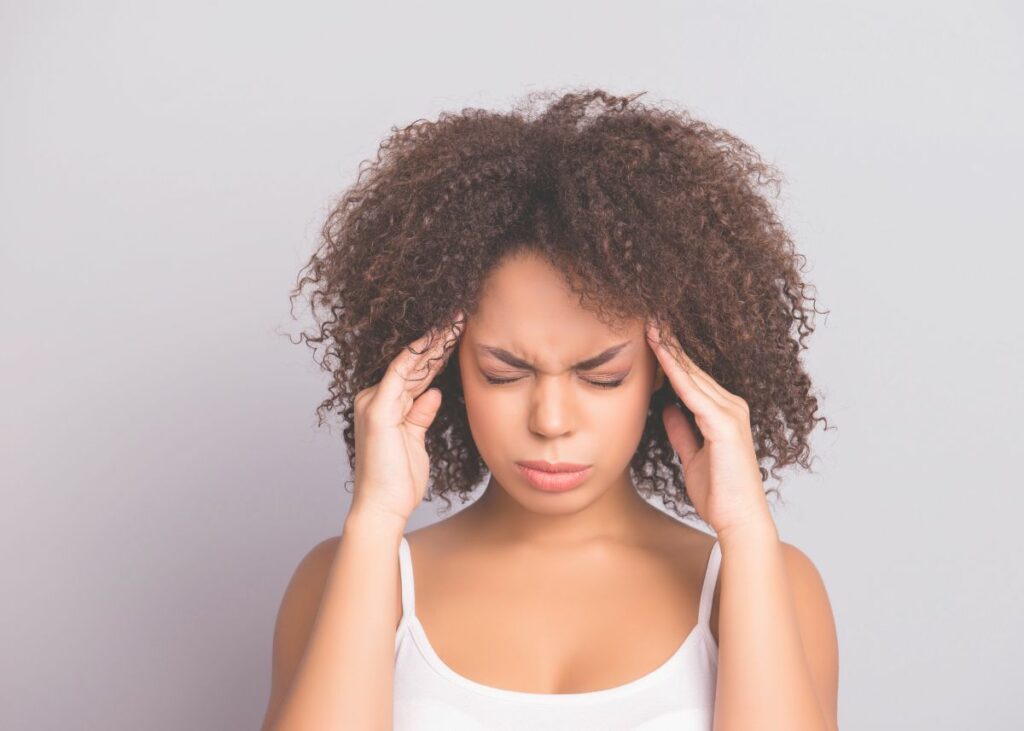 Woman holding her head expressing having a headache after a yoga class. Make.