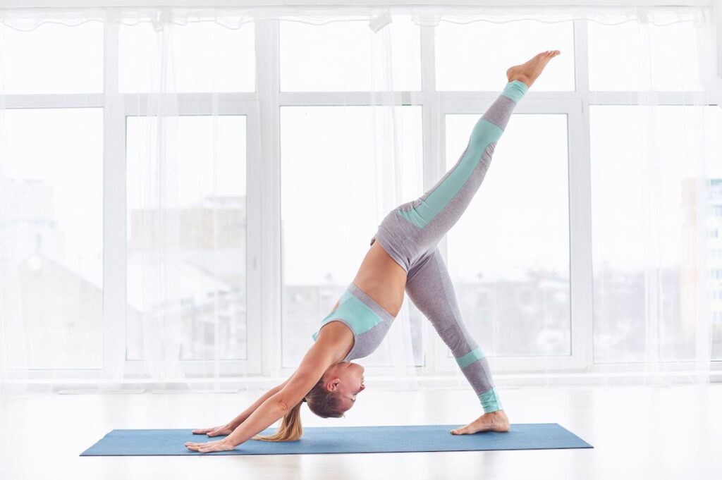 Woman doing one leg downward facing dog yoga pose.