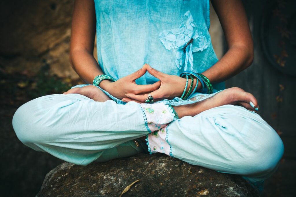 Woman sitting in lotus position with hands in Dhyana mudra.